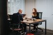 © qunica.com - A professional scene of two people in business attire having an important discussion at a modern office desk, showcasing collaboration, focus, and productive communication.