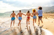 © unai - Five happy friends running on the beach at sunset holding hands