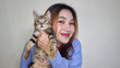 © Said21 Photography  - Beautiful blonde Asian woman very happy holding adorable cat. Woman hugging cute cat isolated on white background. Adorable domestic pet concept.