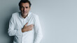 © Frenza - image of a man in his 50s wearing business casual clothes, clutching his chest with both hands, expression of discomfort