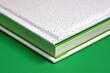© BYAI - Close-up view of a decorative book with white cover and green accents set against a solid green background
