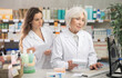 © JackF - Senior female pharmacist helps a female assistant work with a computer in a pharmacy. They enter new arrivals of pills for head, migraine and allergy. Pharmacists work in a pharmacy