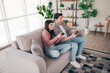 © deagreez - Young couple playing video games at home while enjoying their leisure time together, smiling and bonding in a modern living room interior