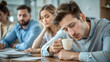 © Margo Miro - Tired young man holding a coffee cup during a meeting with colleagues