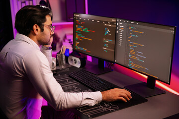 Working smart IT developer analyzing data software development on two pc screen, creating application program updated version online website page system online at neon light cyber office. Surmise.