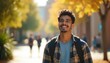 © Viktor - Joyful Latino college student smiles outdoors. Happy young man walks campus, looks up in sunny autumn day. University student with backpack, casual outfit near yellow foliage. Education, lifestyle.