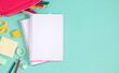 © prime1001 - Back to school. A pencil case with pencils and pens, various office supplies, as well as an eraser, scissors and an open notebook on a light green background. Flat lay, top view