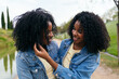 © Koldo_Studio - Two twin sisters are embracing and smiling outdoors, enjoying a special moment together in a park setting