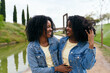 © Koldo_Studio - African two happy twin sisters are laughing and enjoying each other's company in a beautiful park setting