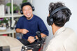 © Gatot - Male Podcaster in Headphones Interviewing Man Guest using Microphone in Broadcasting Studio