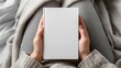 © Strive Studio - Hands holding a blank white book on a lap with soft gray fabric.