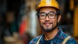 © Artem - A smiling asian construction worker in a hard hat and glasses, ready for work.