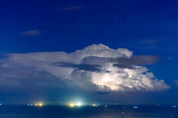 Wall Mural - Powerful cumulonimbus clouds with flashes of lightning over the ocean in the distance
