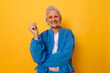 © VISTA by Westend61 - Senior woman in blue jacket smiling against a yellow background