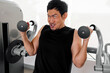 © Sevendeman - Focused Asian man lifting dumbbells with intense facial expression