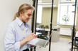 © muse studio - Engaging professional working on laptop while standing in modern office space during the afternoon