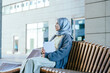 © Iryna - Focused Millennial Muslim Woman Holding Tablet on City Bench