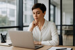 © ณภัทร วงค์มาวิวัฒน์ - Focused Woman in Office: A focused woman, impeccably dressed, is deeply engrossed in her work on a modern laptop in a sunlit office.