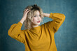 © ADDICTIVE STOCK CORE - Young woman with curly hair in yellow sweater on blue background
