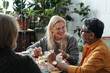 © pressmaster - Group of elderly individuals enjoying lively conversation at cozy cafe. Natural light illuminating faces, creating warm and inviting atmosphere for socializing and connection