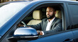 © Nazlykhan - Confident african male adult driving blue car in urban setting