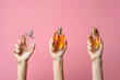 © Aurora frame - Hands holding three perfume bottles with different fragrances on pink background