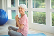© WavebreakMediaMicro - Senior woman wearing workout clothes sitting on blue mat beside exercise ball at home near windows