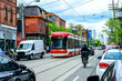 © Michael Connor Photo - public transport: modern tram car  and food delivery bike courrier on city street shot in the queen west area of toronto on a sunny spring day