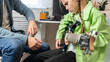 © Mariia - Girl practicing playing electric guitar and her father teaching her, spending a music lesson while sitting on the sofa at home.