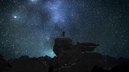 Wall Mural - man on a mountain top watching the starry night sky with stars and the milky way galaxy