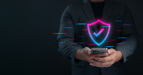 Wall Mural - concept of cybersecurity, businessman holding smartphone with glowing security shield icon, mobile d