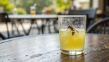 Wasp or Bee Drowning in a Glass of Sweet Drink on Outdoor Cafe Table