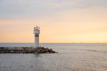 Poster - Bosphorus view at sunset with lighthouse illuminating the shoreline and ships in the distance over calm waters