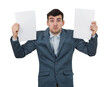 © 1STunningART - Confused young businessman holding two blank papers sheets in his hands isolated on transparent background. Human emotion, face expression life perception concept