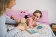 © Studio Marmellata - A mother reads a storybook to her happy toddler on the bed. They share a moment of connection and learning during quiet time at home.