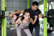 © itchaznong - Supportive Training. Fitness coach assisting woman with barbell squat.