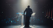 © Gorodenkoff - Anonymous Speaker Welcoming the Audience as He Goes on Conference Stage. Businessman Standing with His Back to Camera, Wearing a Suit, Speaking About Marketing at an International Business Meeting