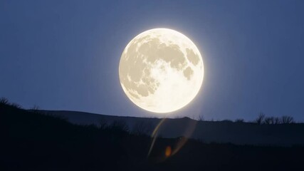 full moon rising over dark hills with clear night sky and soft glow creating calm and peaceful lands