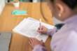 © Studio Marmellata - A young person highlights text on a document with a purple marker while reviewing papers at a wooden desk. This person is focused on their work.