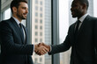 © Zarina - businessmen shaking hands in front of a window.