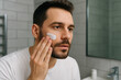 © Zarina - Man shaving his beard in bathroom.