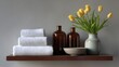 © Alexander Chaykin - A bathroom shelf displaying various items including towels, essential oils, a flower in a vase, and other home decorative elements.