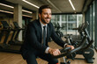 © Zarina - A man in a suit and tie rides a stationary bike.