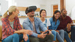 © Monkey Business - Group Of Multi Cultural Friends Playing Computer Game With Virtual Reality Headset At Home