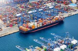 Aerial view of a large container cargo vessel being loaded and unloaded by cranes in a commercial terminal harbour
