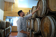 © Kathy Kate - Professional man winemaker working and inspecting wine quality in cellar with wooden barrel in factory. Winery manufacturing industry, Alcohol and winemaking fermentation process.