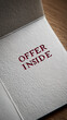 © Mirivox - Close-up of textured off-white paper, red lettering 'Offer Inside' embossed, suggesting a promotional card or invitation, showcasing a hidden offer or message