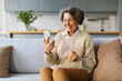 © Home-stock - Happy elderly woman using smartphone at home, making video call, consulting doctor at virtual meeting on mobile phone and smiling at screen