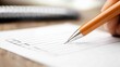 © Phirakhup - A close-up of a person writing on a paper checklist with an orange pen on a wooden table.