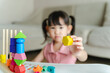 © wanakit - 3 year old girl having fun playing with colorful geometric shape wooden blocks educational toys at home. Selective focus. Childhood and children learning concept.
